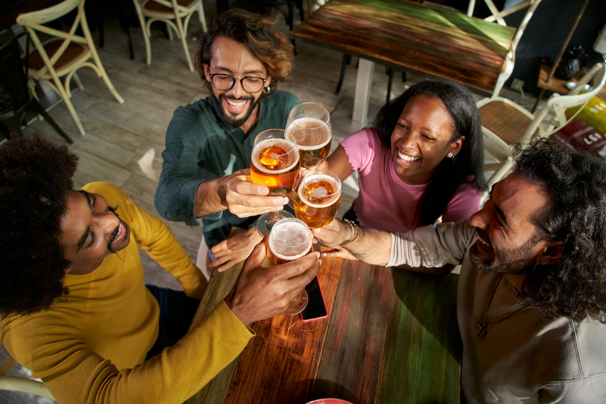 Group of multirracial young people toasting with a pint of beer and celebrating happy hours