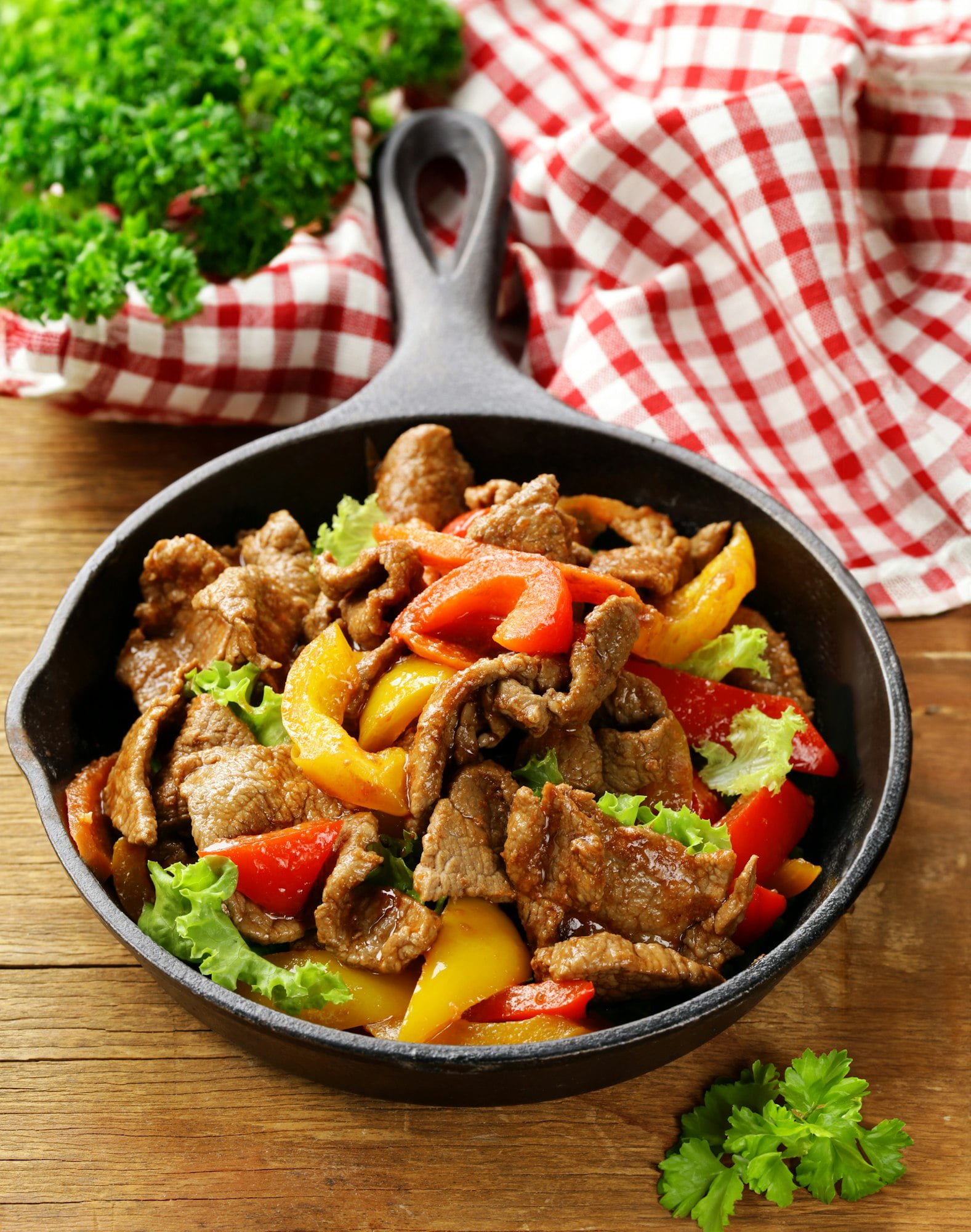 Beef Fajitas with colorful bell peppers in pan and tortilla