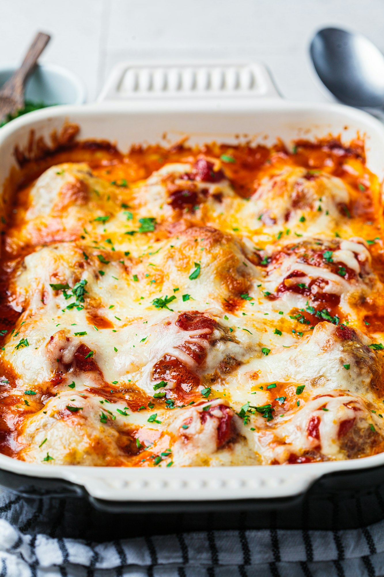 Closeup of baked cheesy meatballs casserole with tomato sauce in the oven dish.