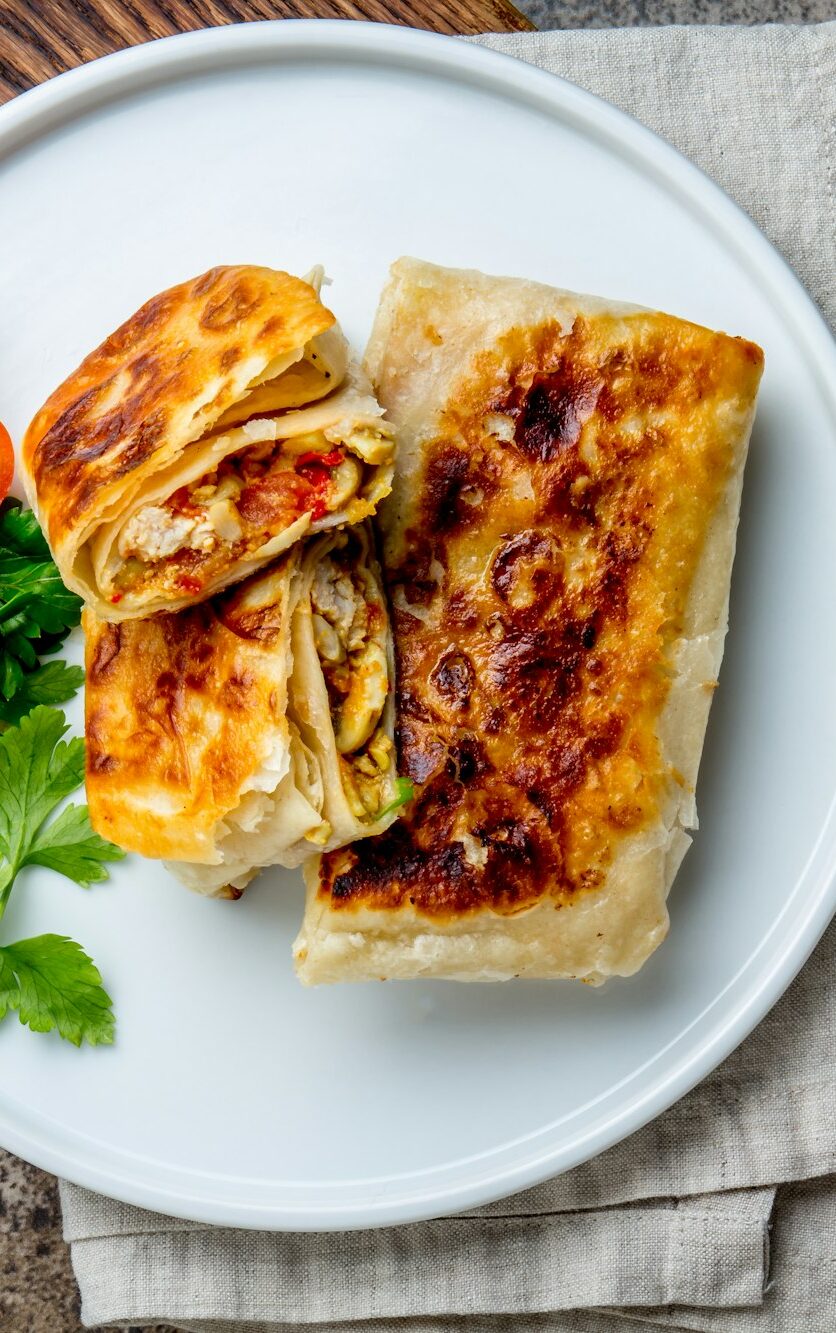 Mexican chimichanga on white plate served with guacamole sauce.