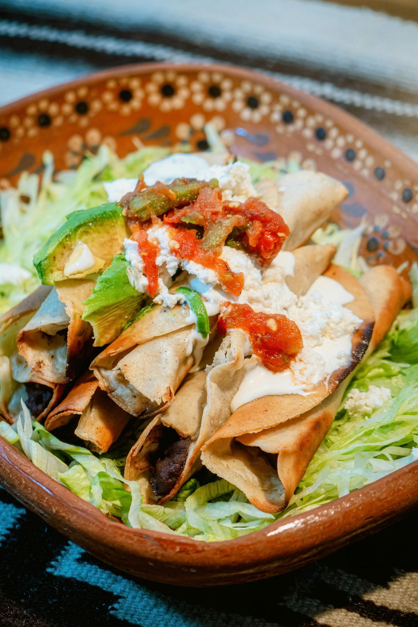 Mexican flautas with lettuce, avocado, cream, sauce and fresh water